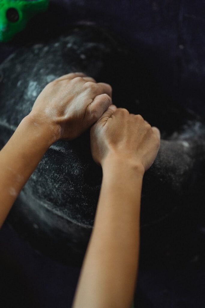 woman with hands in talcum hanging on climbing wall